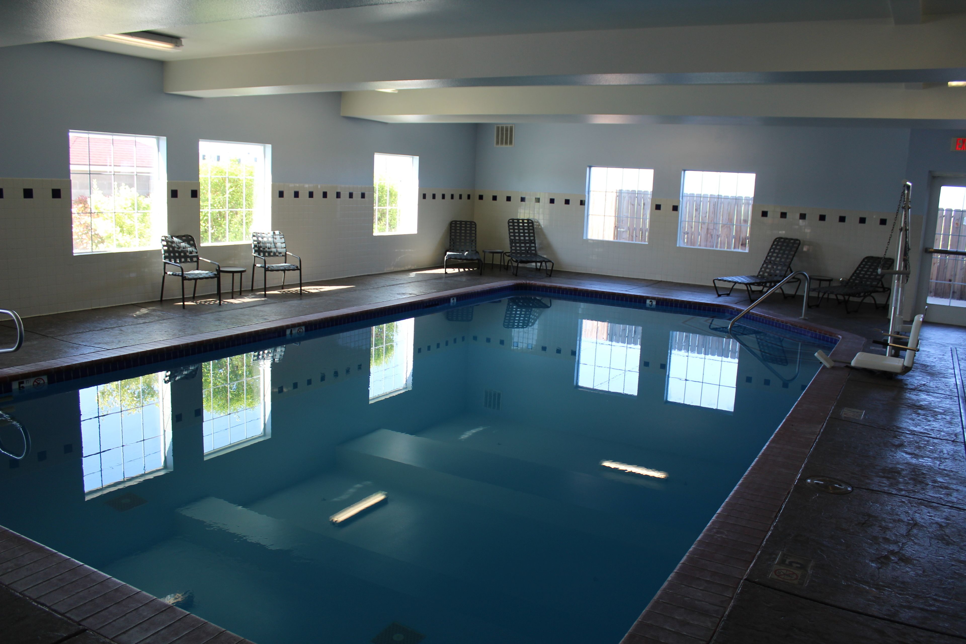 Une piscine intérieure à l’eau d’un bleu cristallin, entourée de fenêtres et baignée de lumière naturelle.