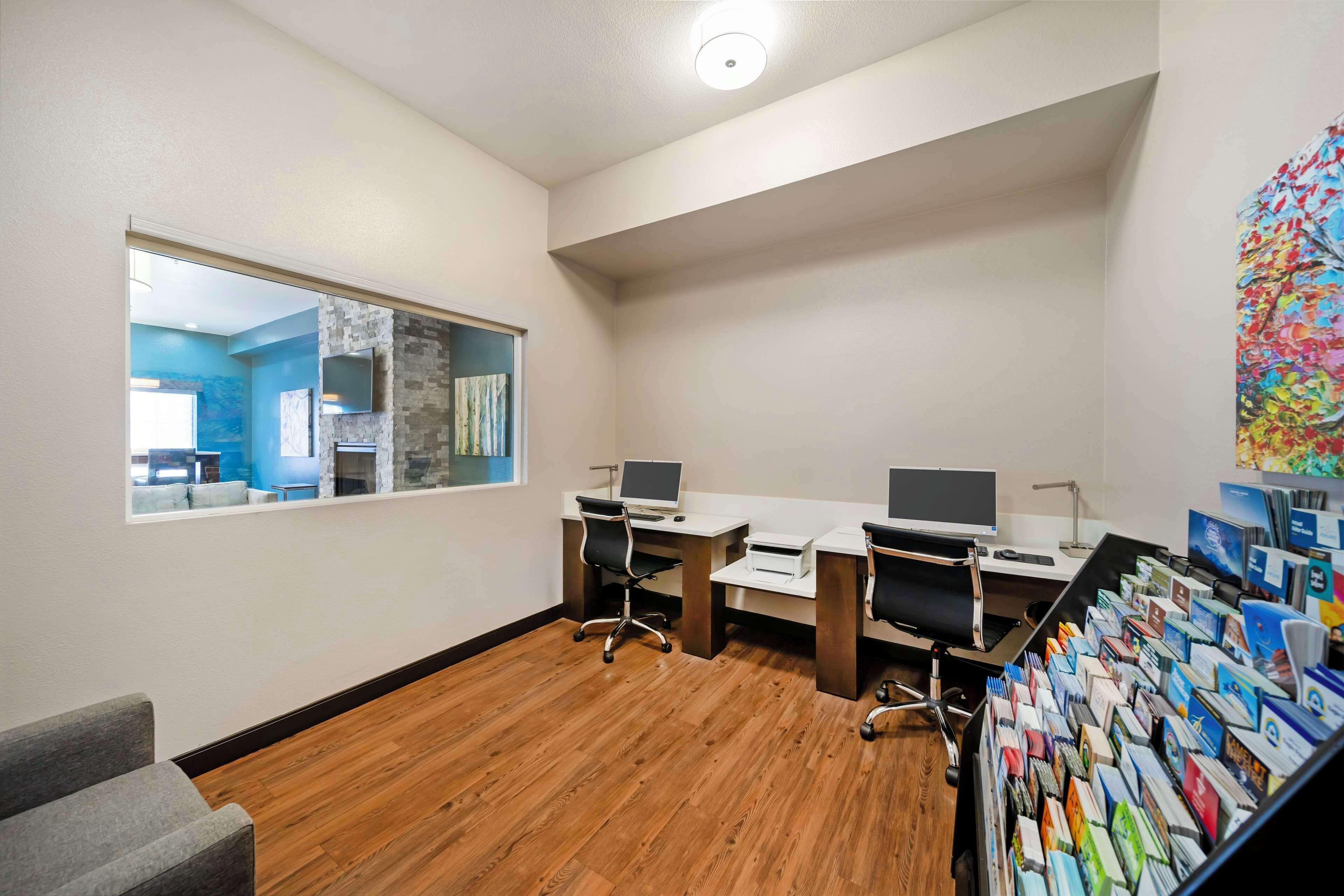 A modern office space with two desks, a bookshelf, and a view of a blue room.