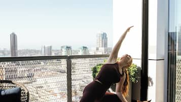 A person performing a yoga pose on a mat in a room with a city view.