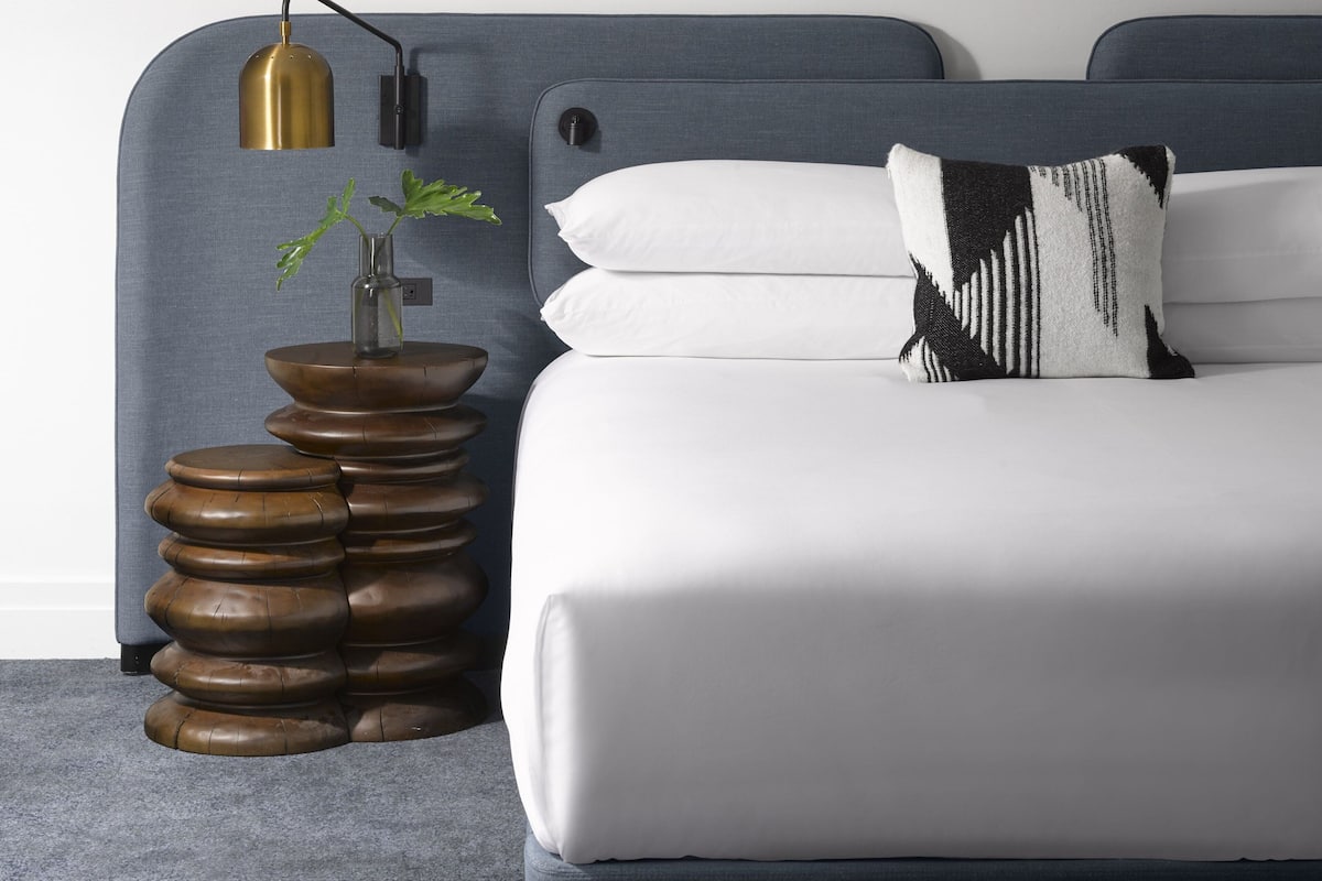 Ein ordentlich eingerichtetes Schlafzimmer mit einem Bett, einem Nachttisch mit Pflanze und einer Lampe.