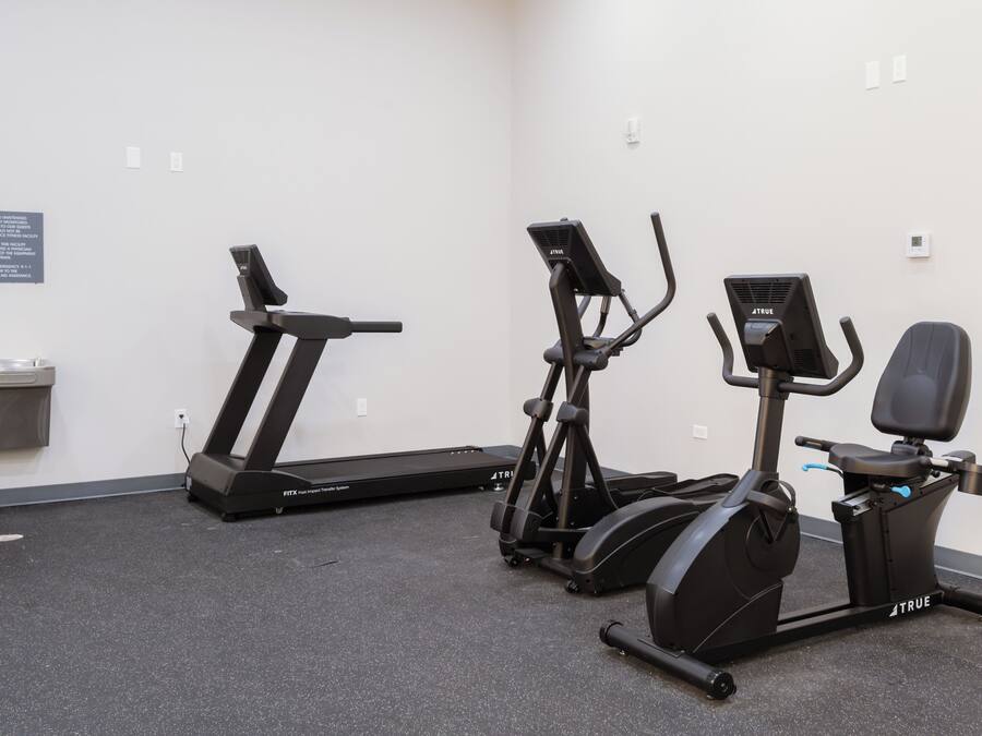 A fitness room with a treadmill, elliptical, and stationary bike.