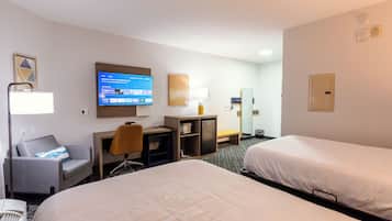 A hotel room with two beds, a desk, a TV, a chair, and a lamp.