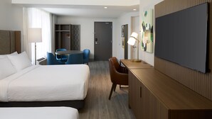 Une chambre d’hôtel avec deux lits, un bureau, une chaise, une télévision et une armoire.
