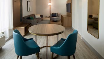 Una sala de estar moderna con una mesa redonda de madera, dos sillas azules, un sofá y una pequeña mesita auxiliar.