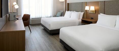 Una habitación de hotel con dos camas, un escritorio, una silla y un televisor.