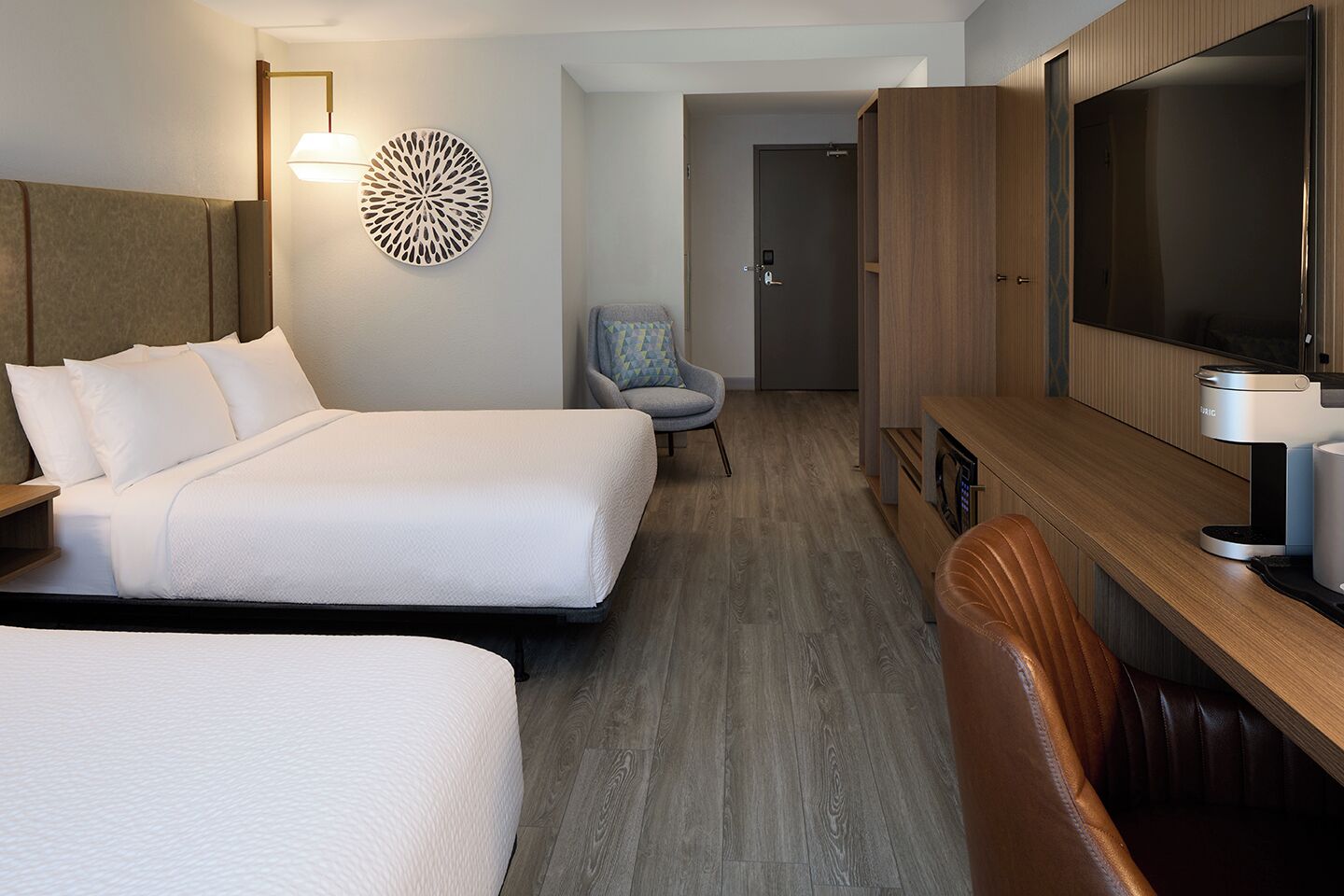 Een hotelkamer met twee bedden, een televisie, een koffiezetapparaat en een stoel.