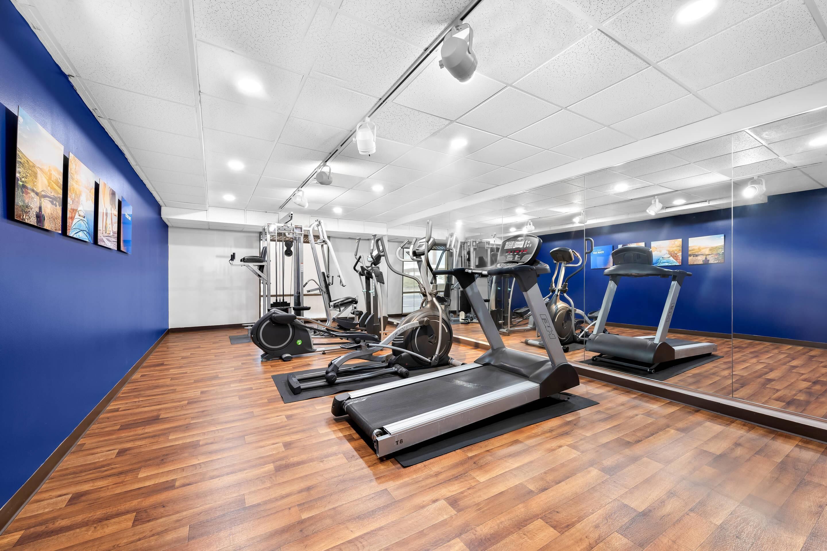 A gym with exercise equipment, wooden flooring, and blue walls.