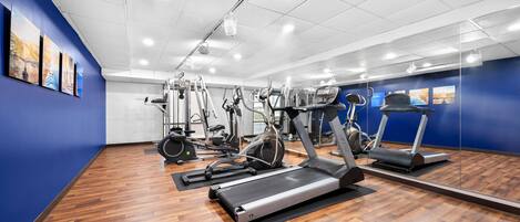 A gym with exercise equipment, wooden flooring, and blue walls.