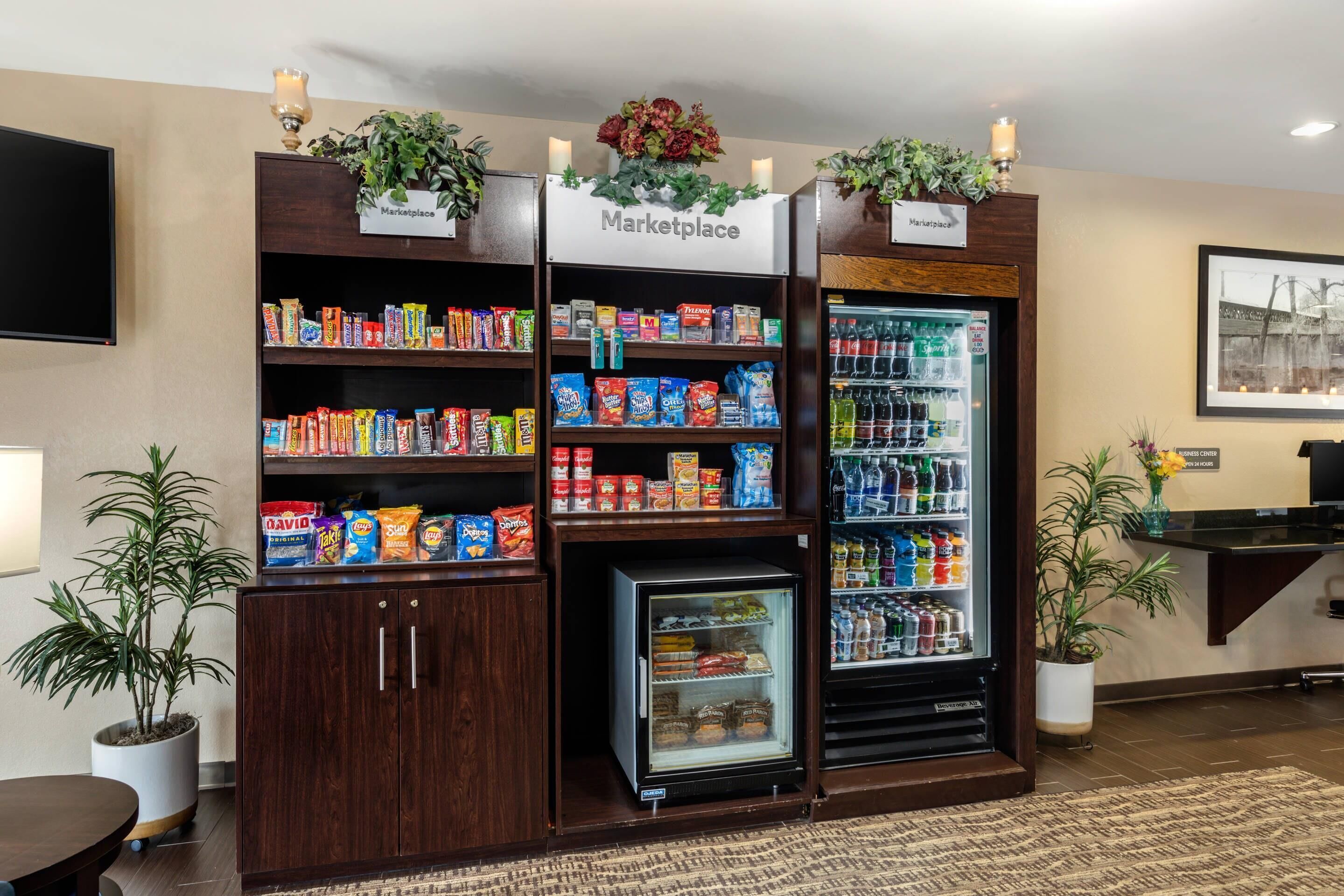 A kitchenette area with a refrigerator, microwave, and pantry shelves stocked with snacks and beverages.