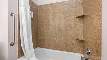 Une salle de bain avec une baignoire blanche, une barre d’appui et un rideau de douche.