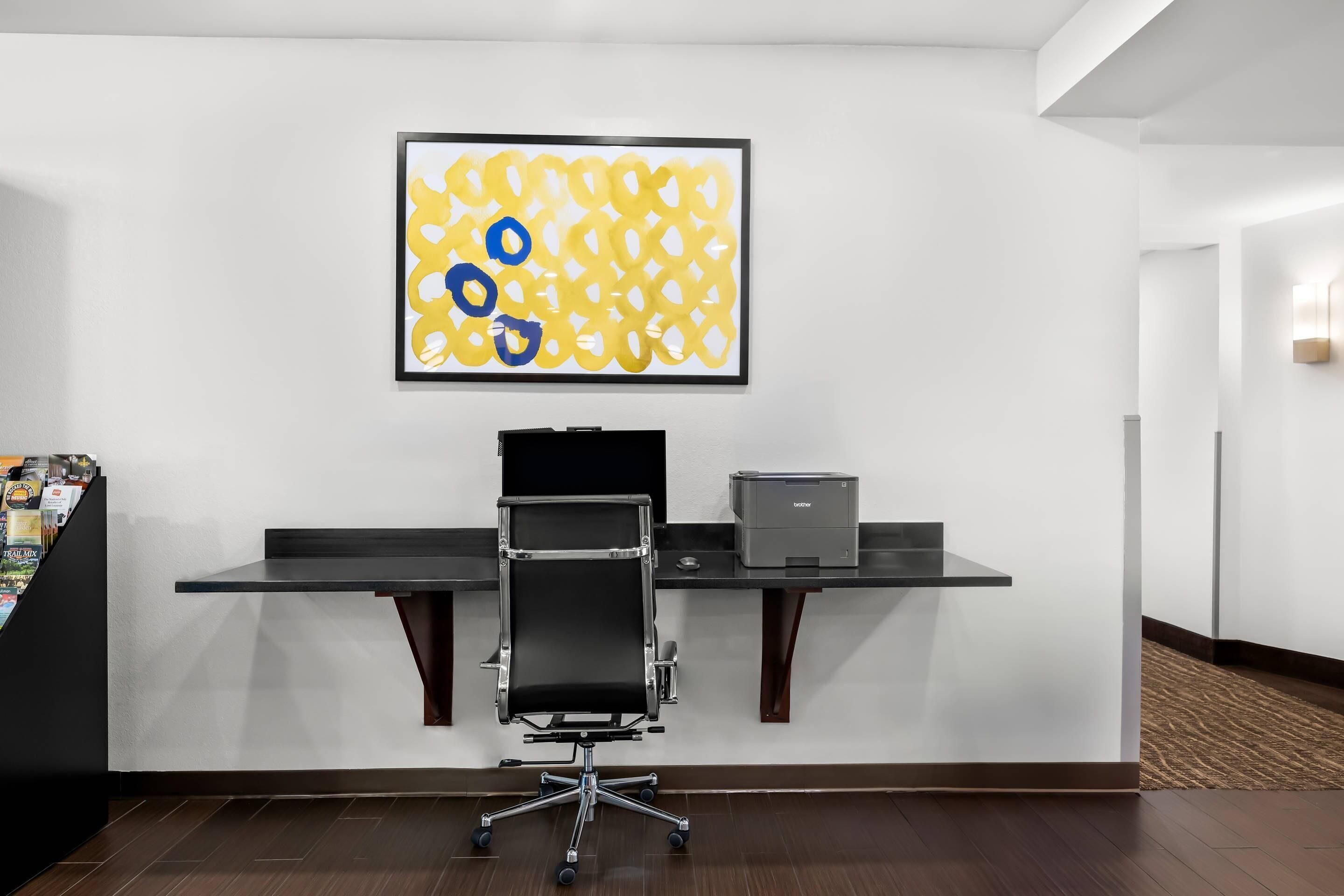 Un moderno spazio ufficio con scrivania, sedia e un quadro astratto appeso al muro.