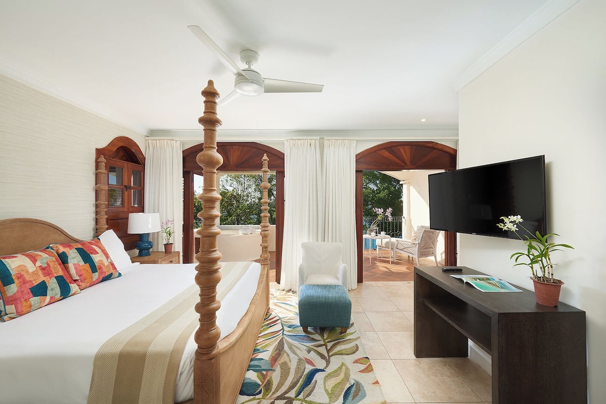 A hotel room with a bed, a TV, a desk, a chair, and a view of the outdoors.