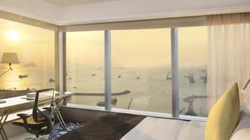 Une chambre d’hôtel avec une grande fenêtre, un bureau avec une chaise, un lit et une lampe.