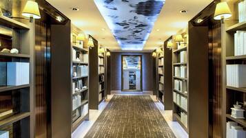 Een hotelgang met boekenkasten aan weerszijden, een kamerbreed tapijt en een plafond met lichtprojectie.