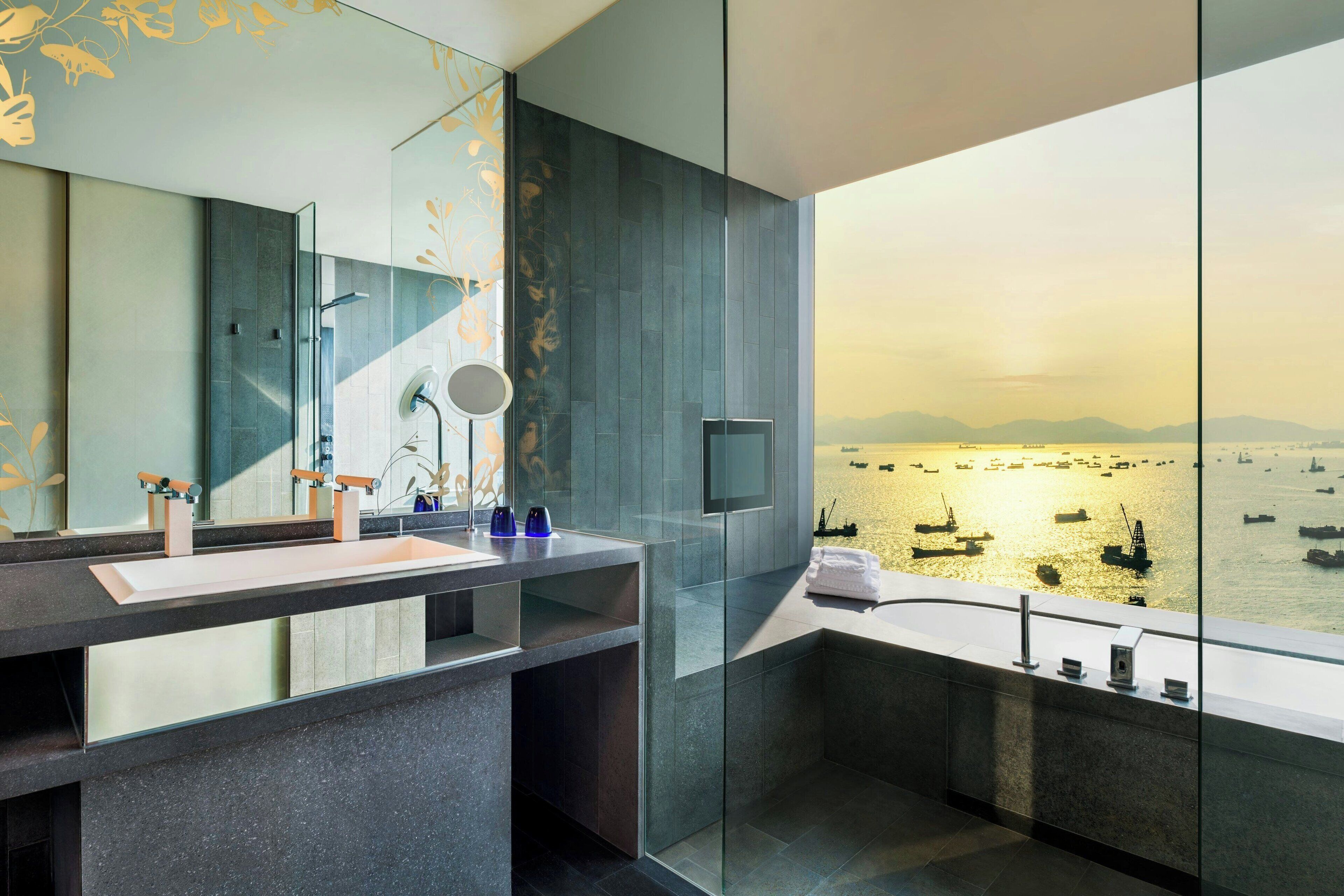 A modern bathroom with a large mirror, a sink, and a glass-enclosed shower area.