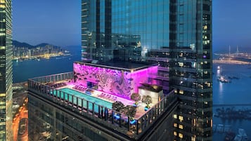 A high-rise building with a rooftop pool area featuring a large mural and seating.