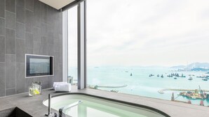 Une salle de bain moderne avec une baignoire, une grande fenêtre et une vue sur la mer.