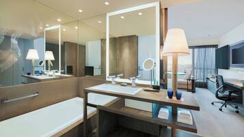 Un baño moderno con bañera, dos lavamanos, un espejo grande y un mueble de tocador con lámpara.