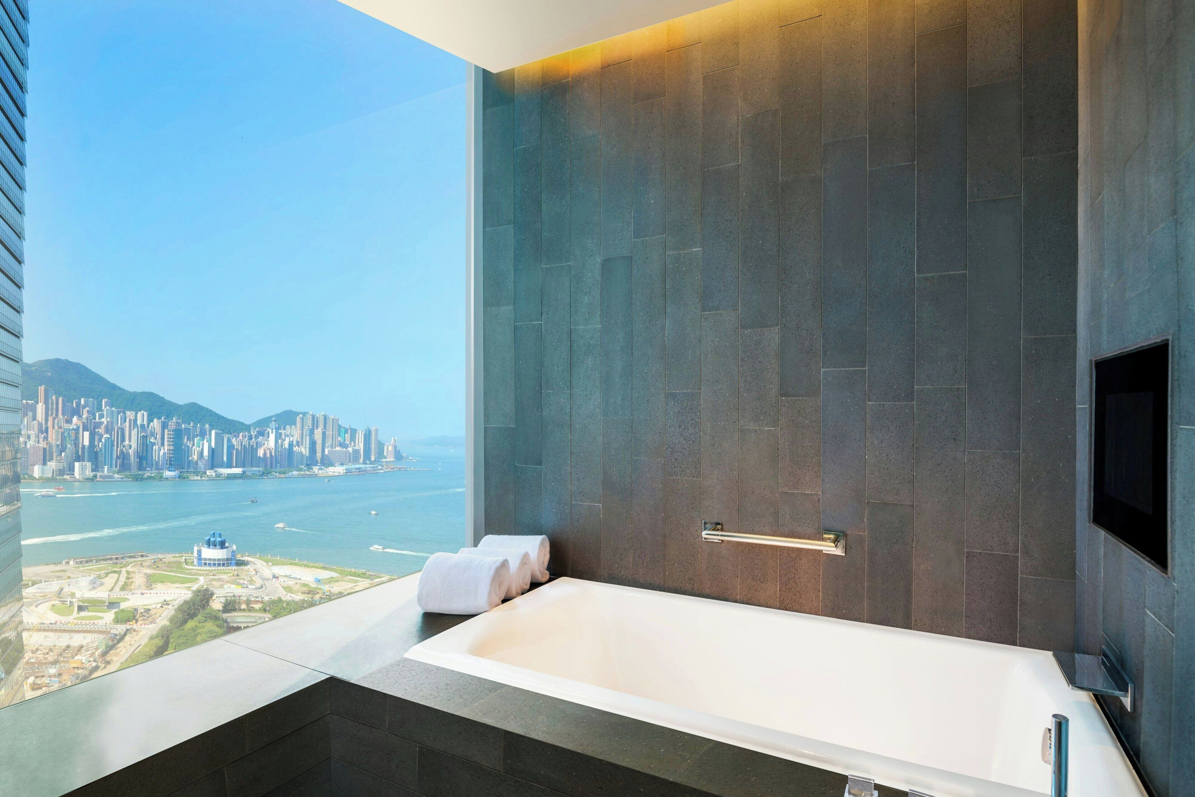 A modern bathroom with a large bathtub, a towel rack, and a television.