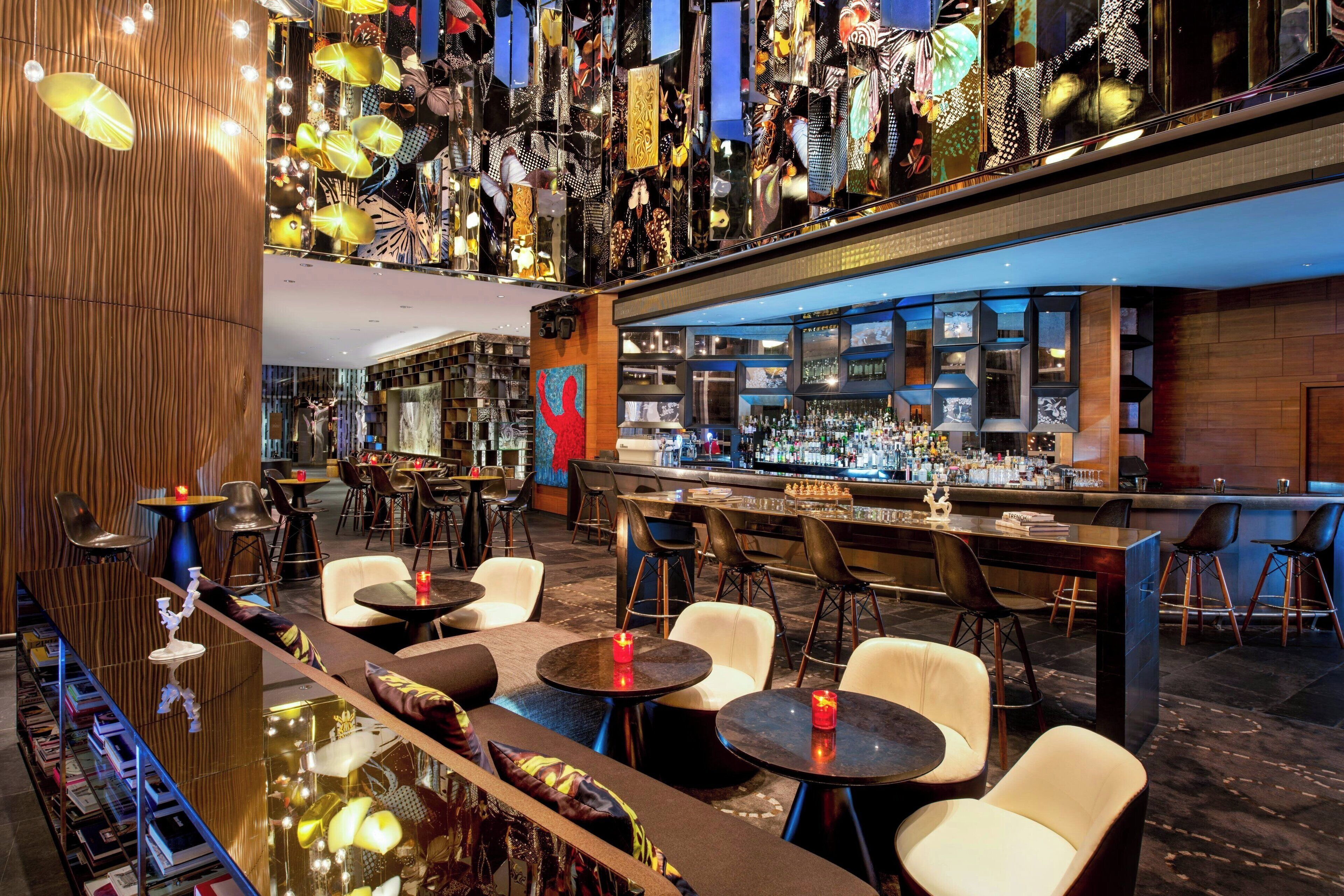 A modern bar area with multiple seating options, including round tables and bar stools.
