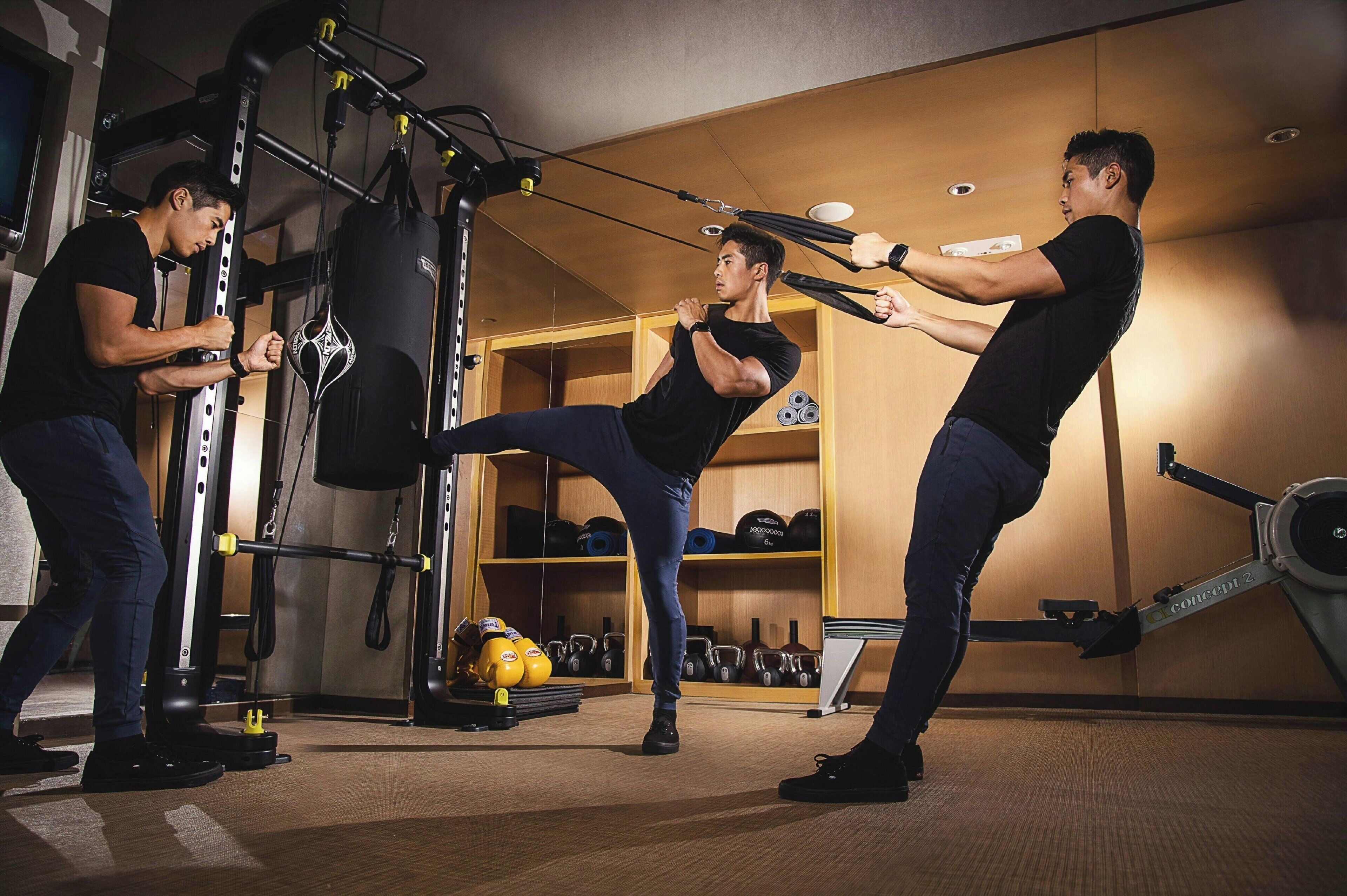 A gym with exercise equipment, including a punching bag, weight plates, and a stationary bike.