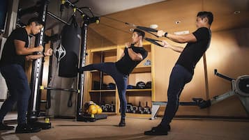 A gym with exercise equipment, including a punching bag, weight plates, and a stationary bike.