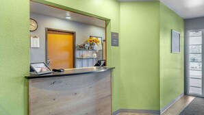 Et receptionsområde med en træreception, et ur og et skilt, der angiver et kontor.