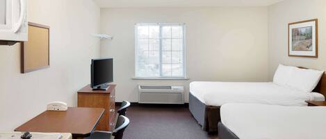 A hotel room with two beds, a desk with a computer, a microwave, and a TV.