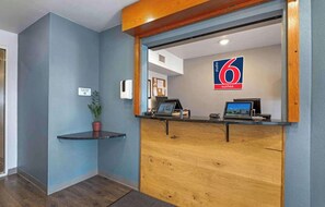 A reception desk with a blue wall, a wooden counter, and a sign indicating '6 suites.' - Studio 6 Extended Stay Cincinnati Sharonville OH (Sharonville)