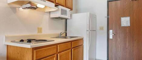 Una cocina compacta con armarios de madera, una estufa blanca, un microondas y un refrigerador.