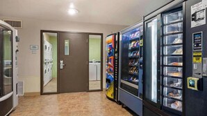 Un hall d’hôtel équipé d’un distributeur automatique, d’un espace dédié à la blanchisserie pour les clients et d’une porte donnant accès à une autre pièce.