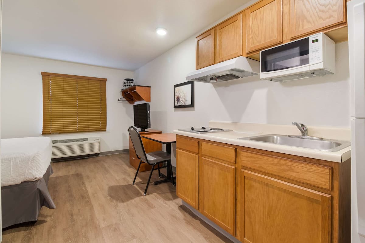 A compact kitchen with wooden cabinets, a microwave, and a sink.