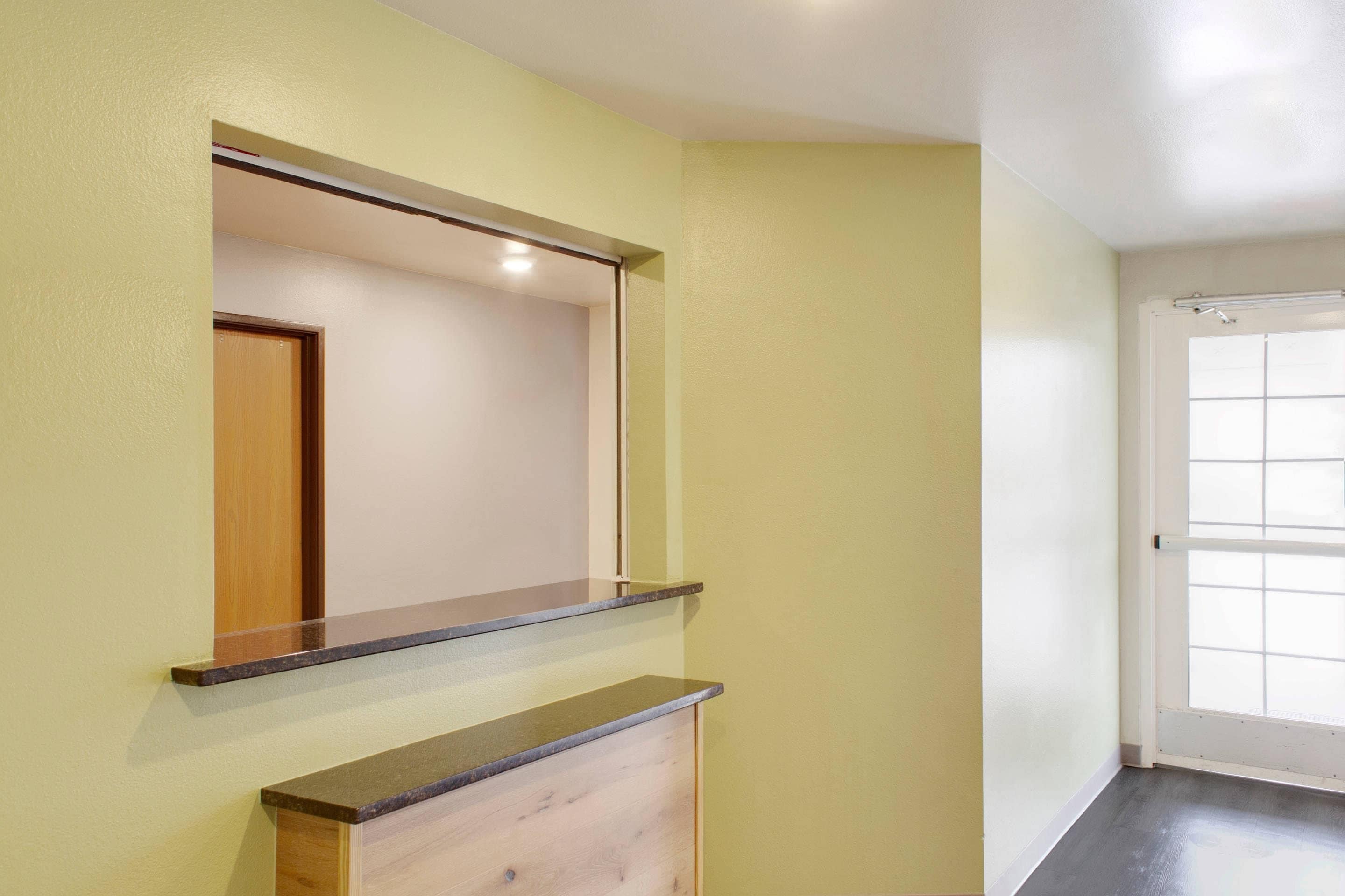 Una habitación con puerta de madera, un espejo y una lámpara en la pared.