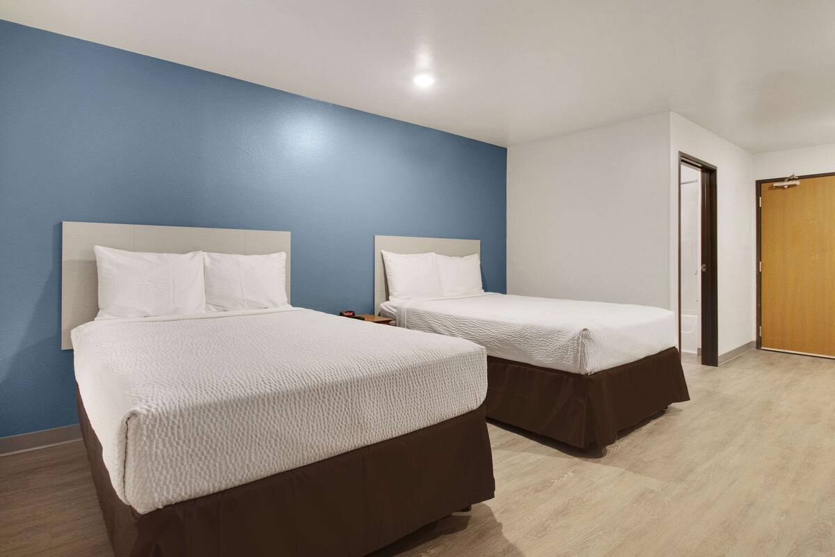 Ett hotellrum med två sängar, ett trägolv och en blå accentvägg.