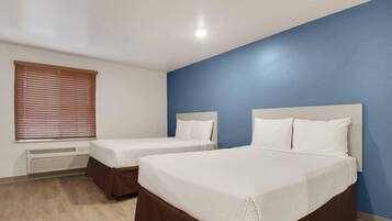 Una habitación de hotel con dos camas, una ventana con persianas y un calentador de pared.