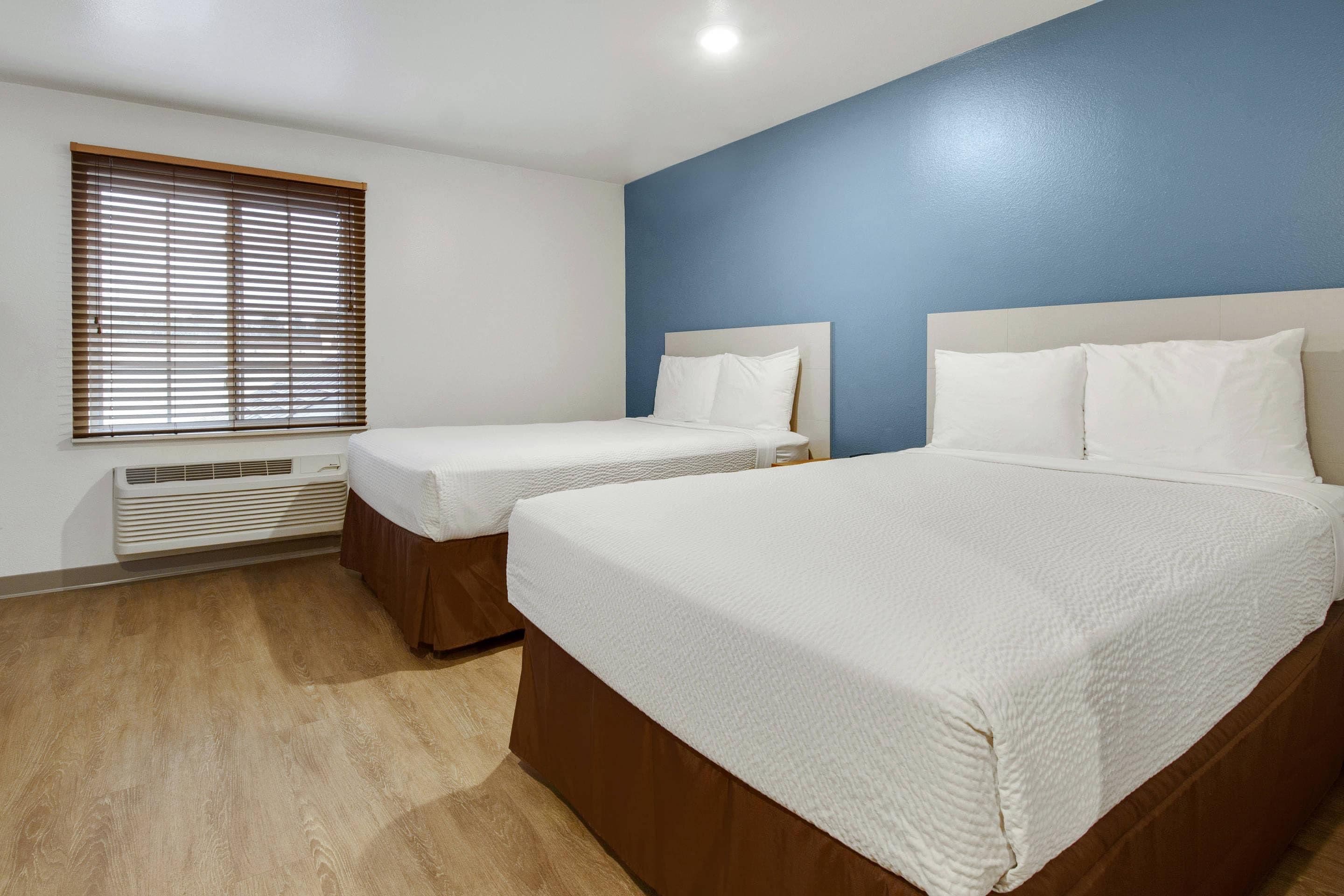 Habitación de hotel con dos camas, una ventana con persianas y un calentador de pared.