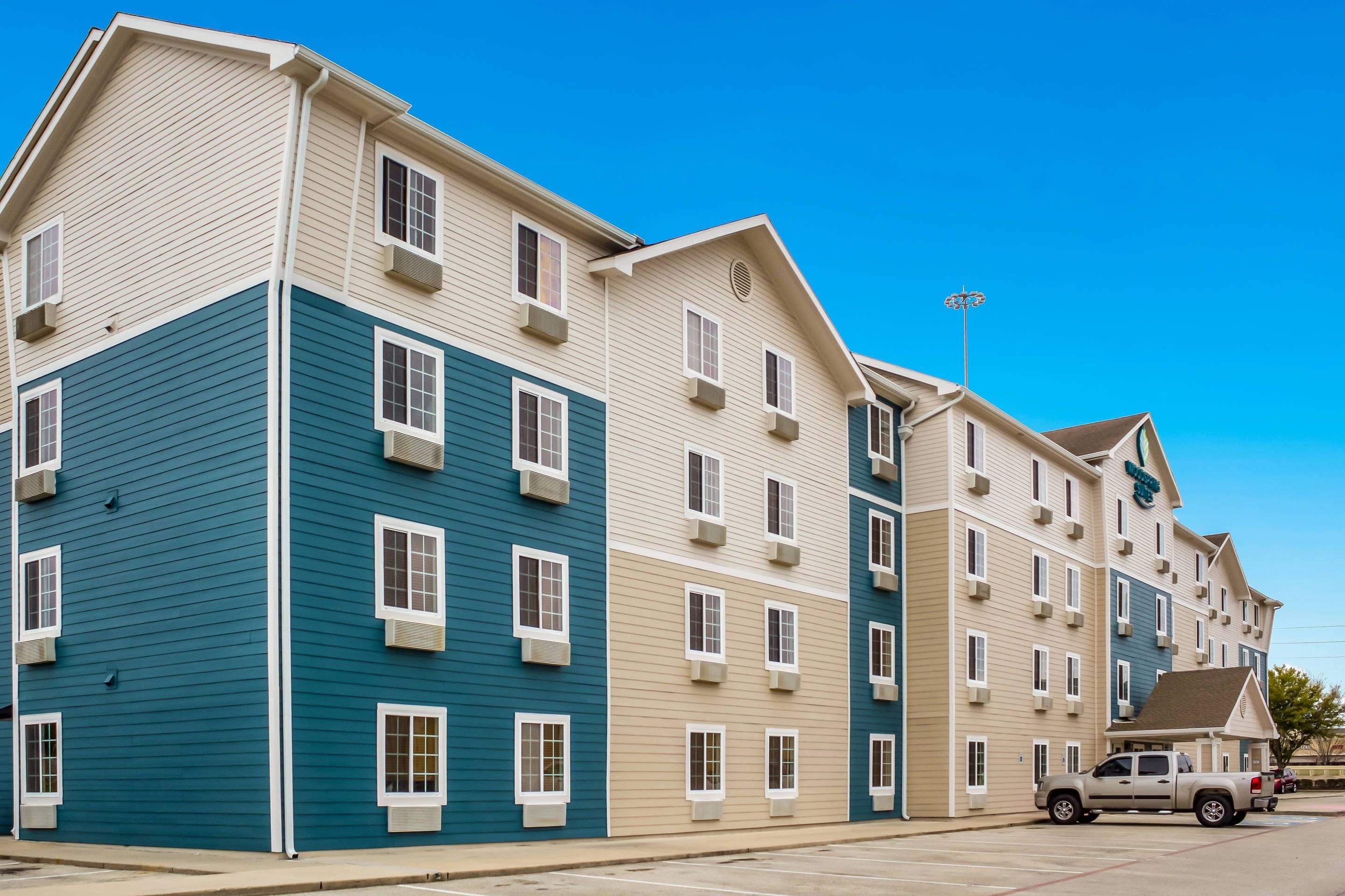 A multi-story hotel with a parking lot and a pickup truck.