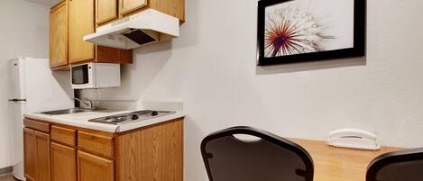 A compact kitchen with wooden cabinets, a microwave, a stove, and a dining area with a table and chairs.