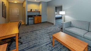 A hotel room with a kitchenette, a sofa, a dining table, and a lamp. - La Quinta Inn & Suites by Wyndham Bridgeport (Bridgeport)