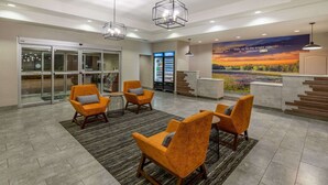 A lobby with a reception desk, a mural, and seating area with chairs. - La Quinta Inn & Suites by Wyndham Bridgeport (Bridgeport)