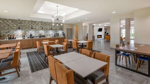 A modern hotel lobby with a central bar area, multiple seating arrangements, and a visible fireplace. - La Quinta Inn & Suites by Wyndham Bridgeport (Bridgeport)