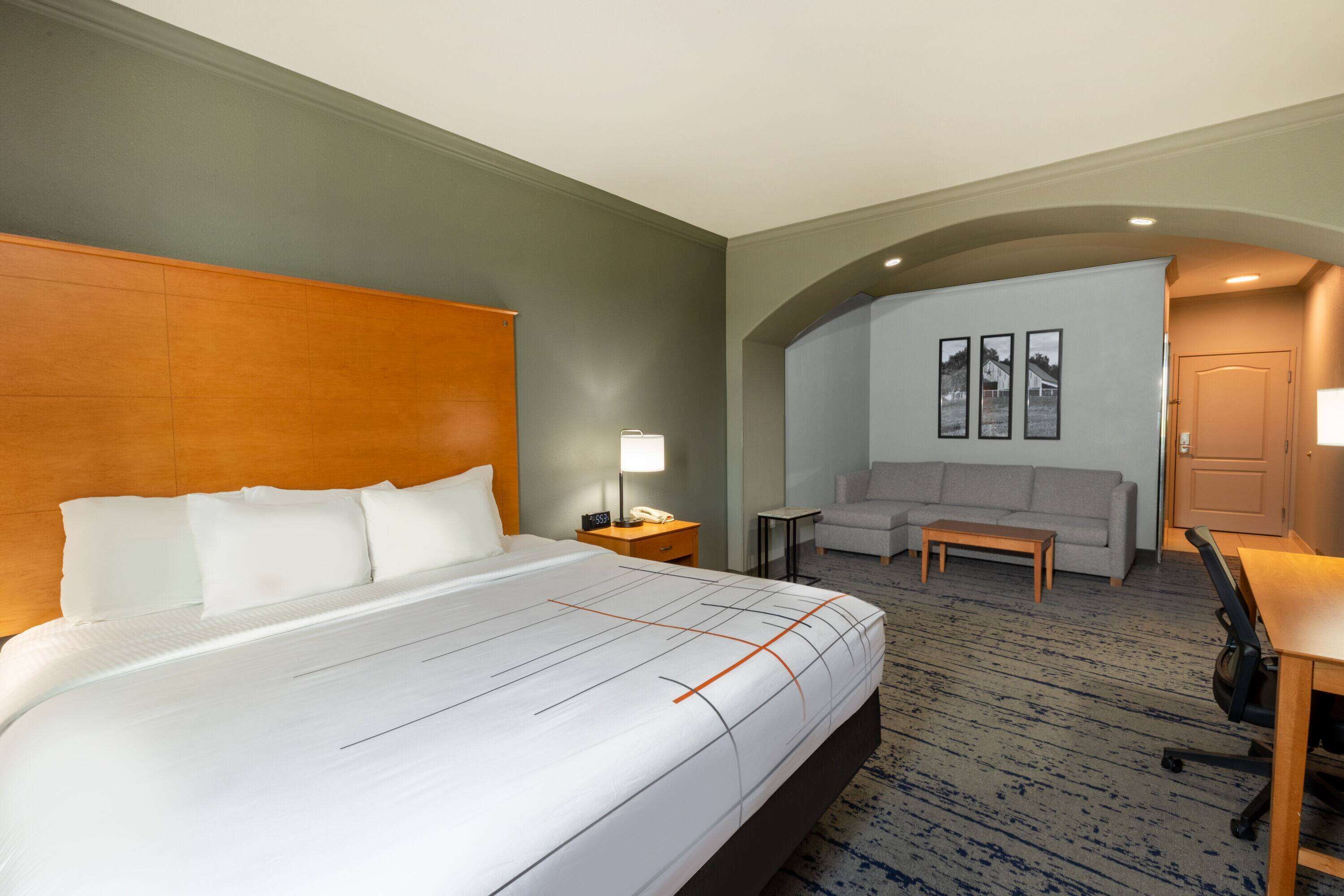 A hotel room with a large bed, a sofa, a desk, and a small table.