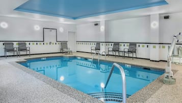 Zona de piscina d'hotel amb una piscina blava cristal·lina, seients al voltant i un sostre amb detall blau.