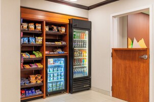 Un depósito con estantes llenos de refrigerios y un refrigerador con bebidas.