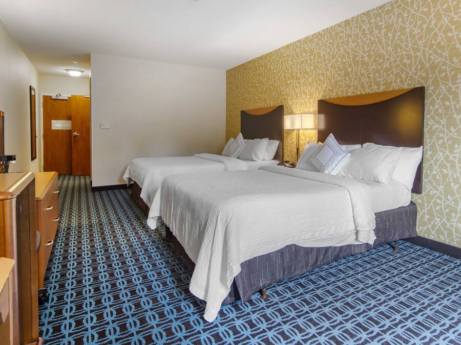 Ein Hotelzimmer mit zwei Betten, einer Holzkommode und einem gemusterten Teppich.
