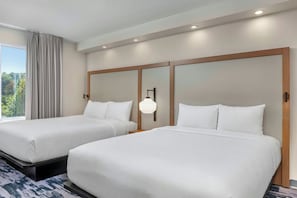 Habitación de hotel con dos camas, un ventanal con cortinas e iluminación empotrada en el techo.