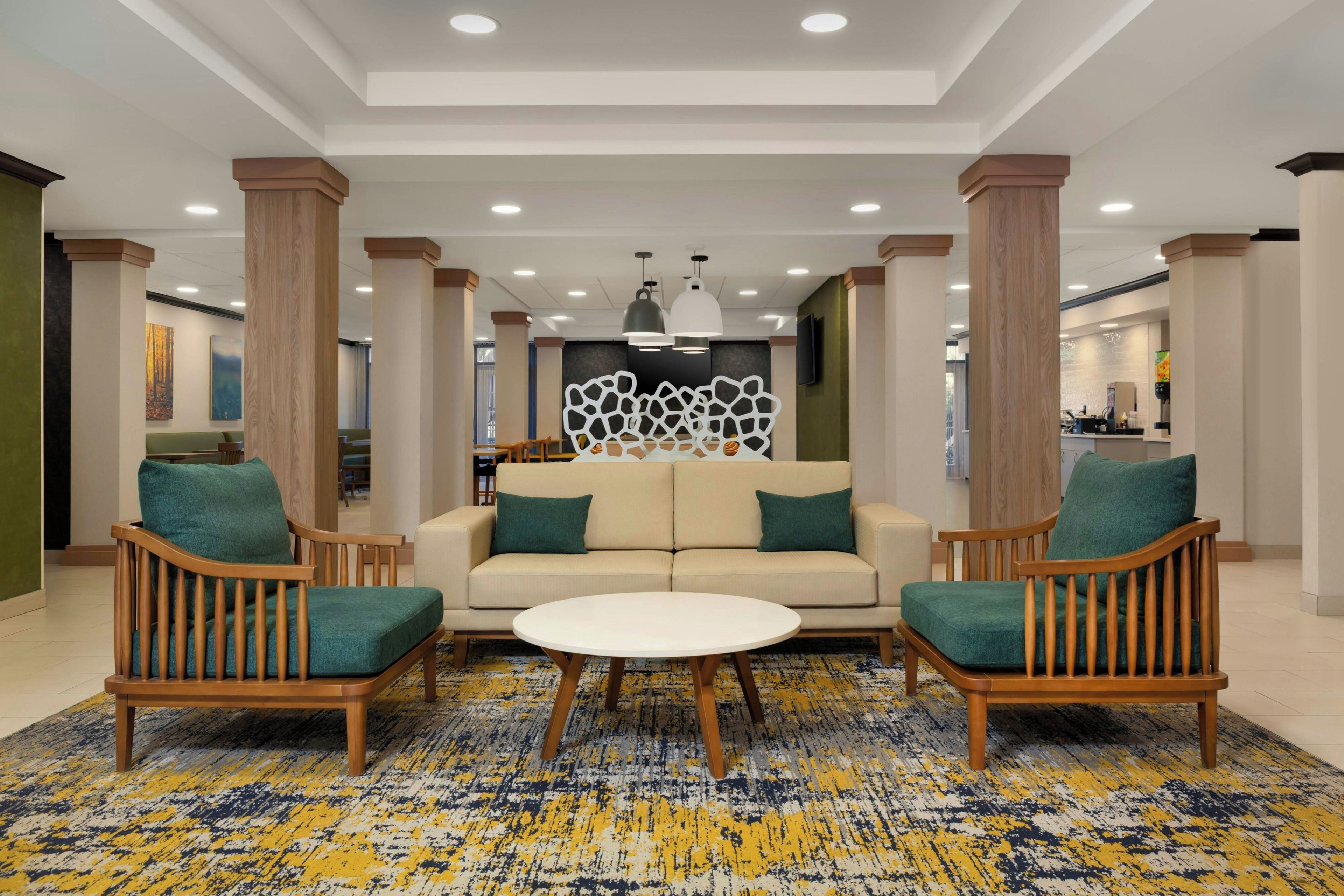 A lobby with a sofa, two armchairs, a coffee table, and a patterned carpet.