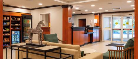 A lobby with a reception desk, seating area, and vending machines.