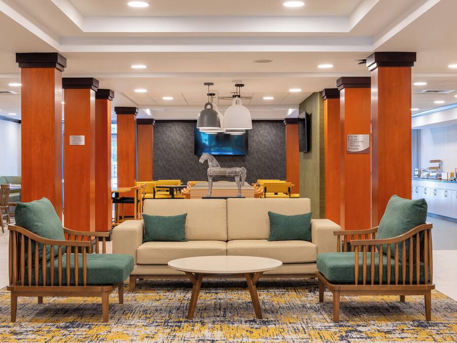 A lobby with a sofa, chairs, a coffee station, and a dining area.