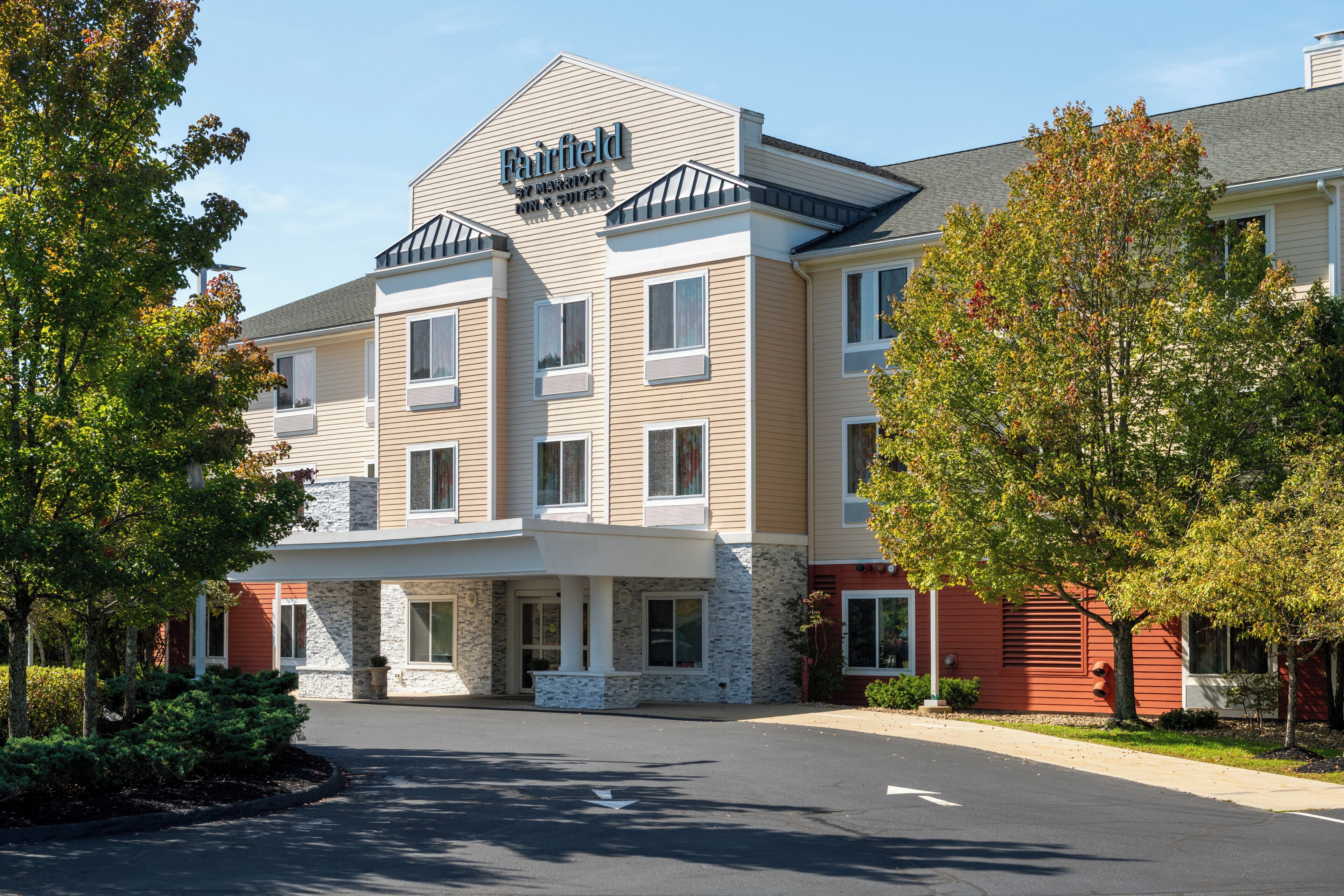 A multi-story hotel with a prominent sign, a covered entrance, and a parking lot.